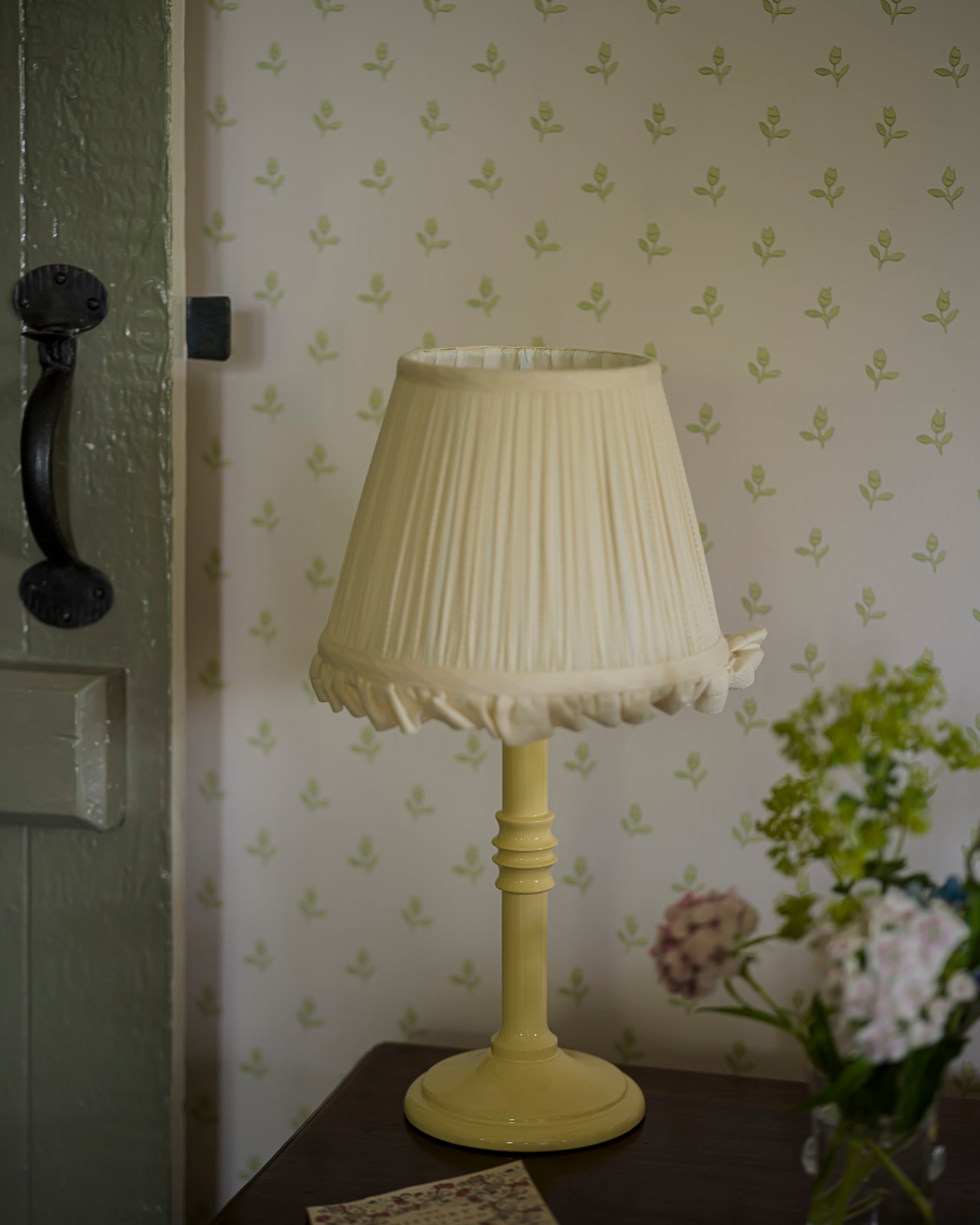 Small lacquered lampstand in buttercup on set of drawers